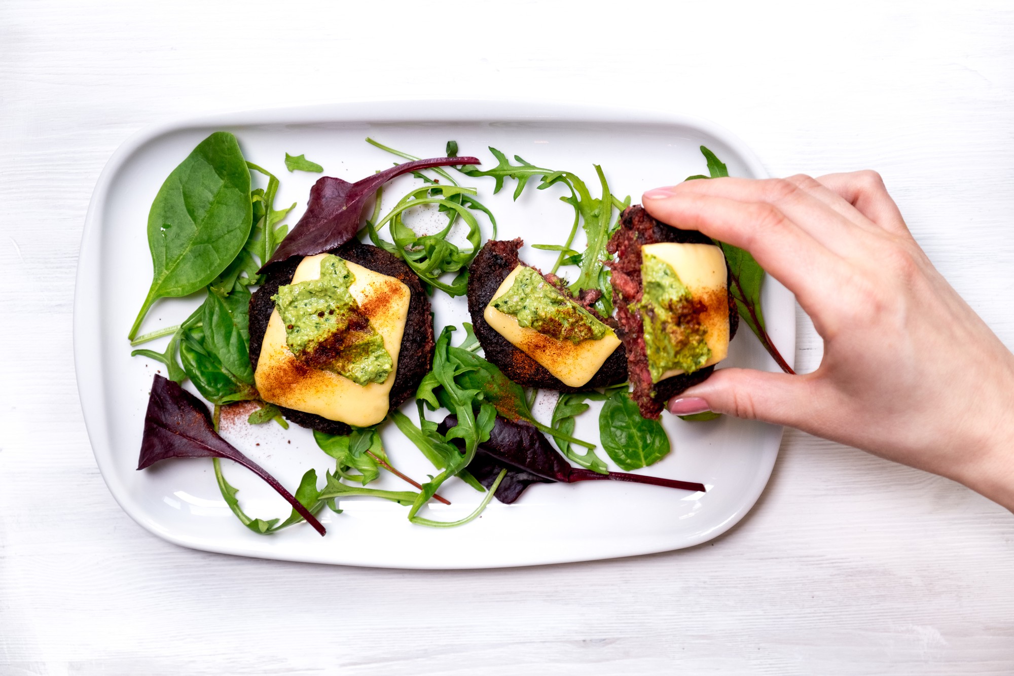 Hand plating a colorful salad with herbs